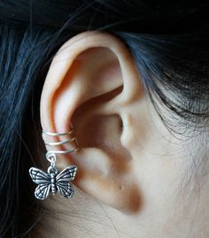 a close up of a person's ear with a butterfly ring on top of it