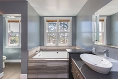 a bathroom with a tub, sink and large window