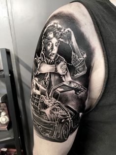 a man's arm with a black and white tattoo on it, featuring an image of a woman driving a car