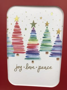 a card with watercolor christmas trees and the words joy love peace