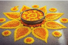 a pot filled with yellow flowers sitting on top of a cement floor covered in petals