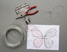 some wire and scissors are laying out on the table next to it is a piece of paper with a butterfly drawn on it