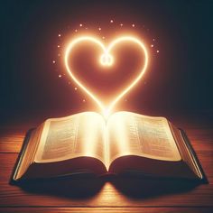 an open book with a heart shaped light coming out of it