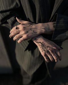 a person with tattoos on their arms and hands is holding onto another persons hand while wearing a pinstripe suit