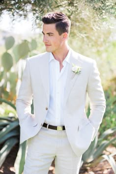 a man wearing a white suit and flower in his lapel