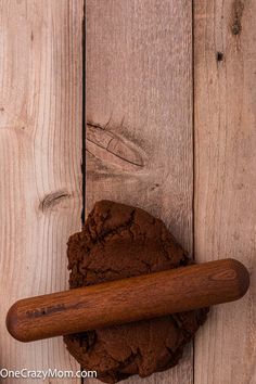 a piece of chocolate cake next to a rolling pin on a wooden surface with wood planks