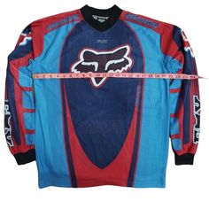 a blue and red jersey with the word fox on it, measuring tape in front of it