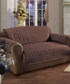 a living room filled with furniture covered in grey and brown covers next to a fire place