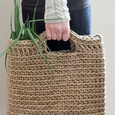 a person holding a large woven bag with grass in the front and bottom part of it