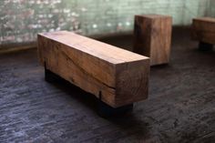 two wooden benches sitting next to each other on top of a hard wood floor in front of a brick wall