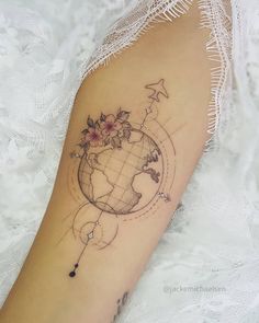 a woman's arm with a small globe tattoo on the left side of her arm