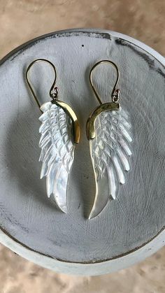 two pairs of angel wings are hanging from gold earwires on a silver plate