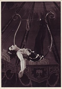 an old fashion photo of a woman hanging upside down on a rope with her hands in the air