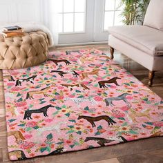 a pink rug with horses and flowers on the floor in front of a chair next to a window