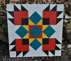 a colorful quilt sitting on top of a pile of rocks