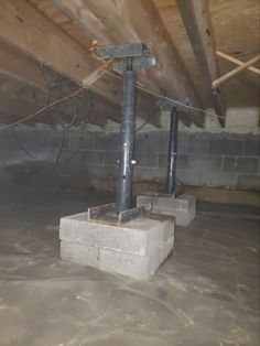 an unfinished attic with exposed pipes and concrete blocks on the floor, in need of repair or remodeling