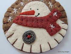 a felt snowman ornament with a button on it