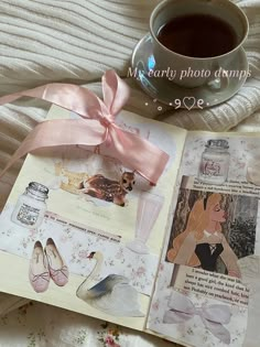 an open book with pictures and a pink bow on the cover next to a cup of coffee