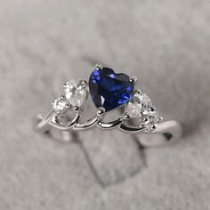 a heart shaped blue sapphire ring with three pear shaped diamonds on the sides and an oval diamond in the middle