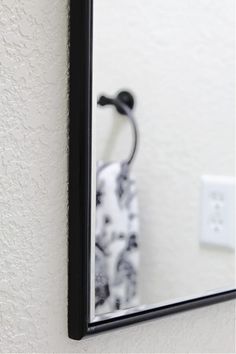 a black and white towel is hanging on the wall in front of a mirror with an electrical outlet