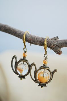 the earrings have been made to look like teapots and are hanging from a branch