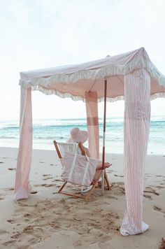 a beach chair under an umbrella on the sand