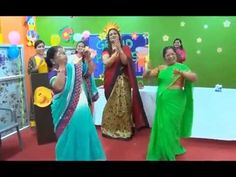 two women in sari dancing on stage with other people behind them and balloons hanging from the ceiling