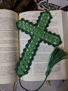 an open book with a crocheted cross on it