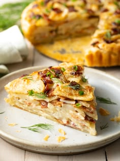 a slice of quiche on a plate with the rest of the pie in the background