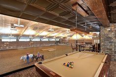 two people on horses are playing pool in an indoor horse show area with stone walls and flooring