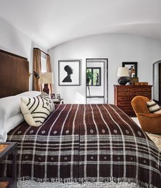 a bedroom with a bed, chair and pictures on the wall