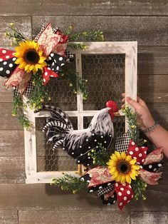 a rooster and sunflower wreath hanging on a window sill next to a chicken