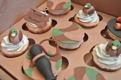 cupcakes decorated with green and brown icing are in a box on the table