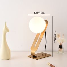 a table lamp sitting on top of a white desk next to a pen and pencil