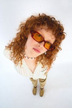 a woman with red curly hair wearing sunglasses