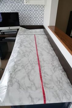 a white marble counter top with red tape on it and a computer in the background