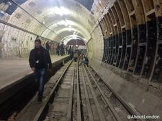 a man is walking down the train tracks in a tunnel with people on either side