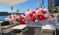 a bunch of balloons that are on the side of a boat near some tables and couches