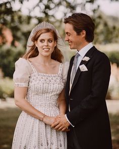 a man in a suit and tie standing next to a woman in a wedding dress