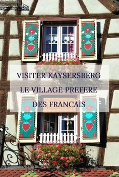 an old building with flowers in the windows and words written below it that read visiter kayersberg, le village preere des francais