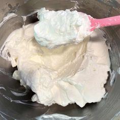 a mixing bowl filled with whipped cream and a pink spoon