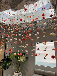 a living room filled with lots of colorful balls and flowers hanging from the skylight