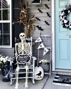 a skeleton sitting on a chair in front of a house decorated for halloween with decorations