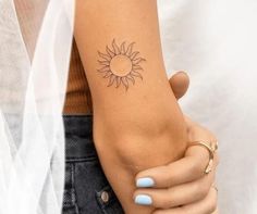 a woman's arm with a small sun tattoo on the left side of her arm