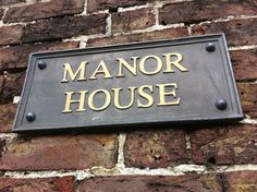 a sign that is on the side of a brick building saying manor house in gold lettering