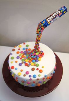 a birthday cake decorated with sprinkles and a candy bar sticking out of it