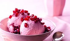 two scoops of ice cream with pomegranate on top in a bowl