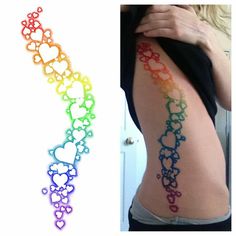 the back of a woman's stomach with rainbow colored tattoos on her side and an image of a line of hearts