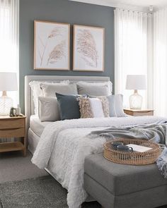 an instagram photo of a bedroom with gray walls and white bedding, two framed pictures on the wall