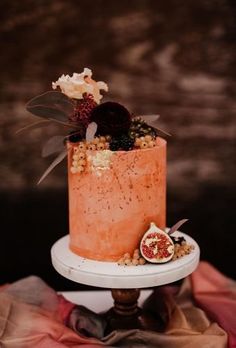 a cake that is sitting on top of a stand with flowers and nuts in it